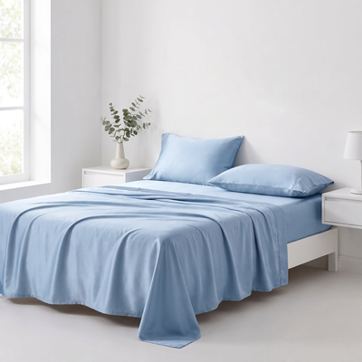 Sky blue cooling silk sheet set made up on a bed in a bright bedroom