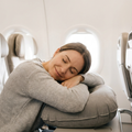 Woman leaning forward napping on the Solvrly Cloud Rest travel pillow on a plane