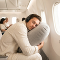 Man resting forward on the Solvrly Cloud Rest inflatable travel pillow on a plane