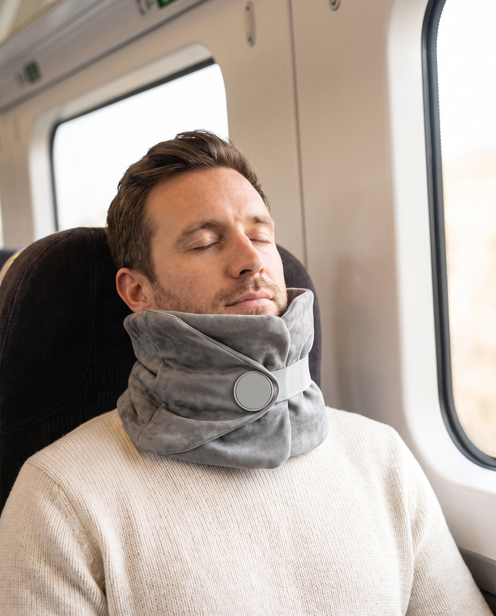 Man dozing on a train wearing the Solvrly Wrap Travel Pillow